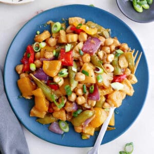 chickpea stir fry with pineapple and vegetables on a plate with a fork