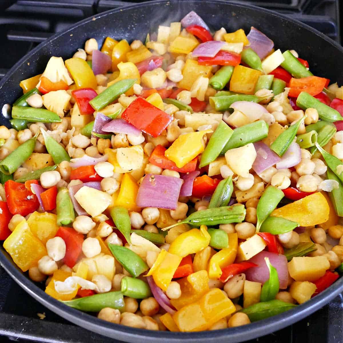 ingredients for pineapple chickpea stir fry cooking in a large skillet