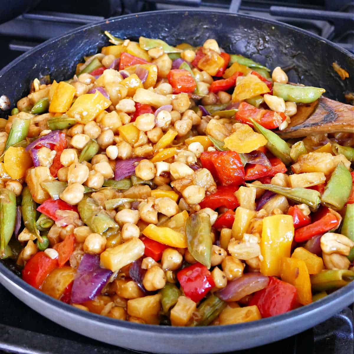chickpea stir fry coated with pineapple sauce cooking in a large skillet