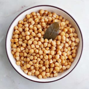 cooked chickpeas in a serving bowl with a bay leaf
