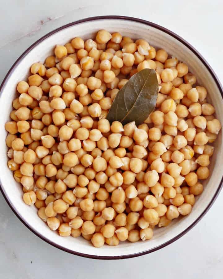 cooked chickpeas in a serving bowl with a bay leaf