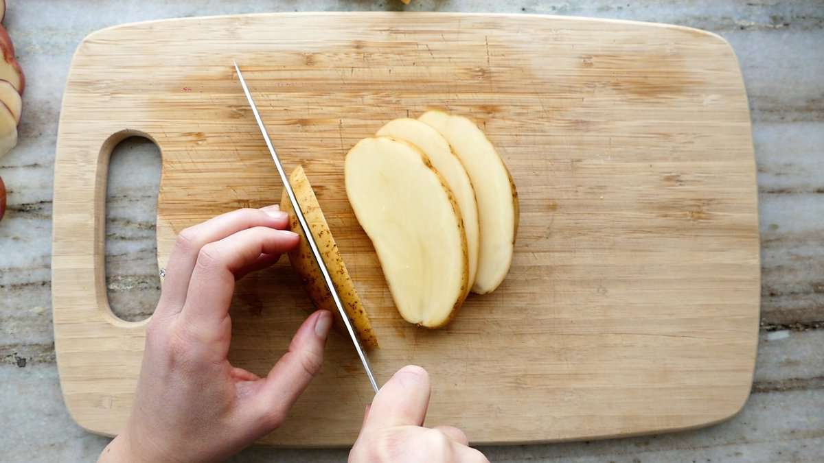woman cutting a russet potato into lengthwise slices