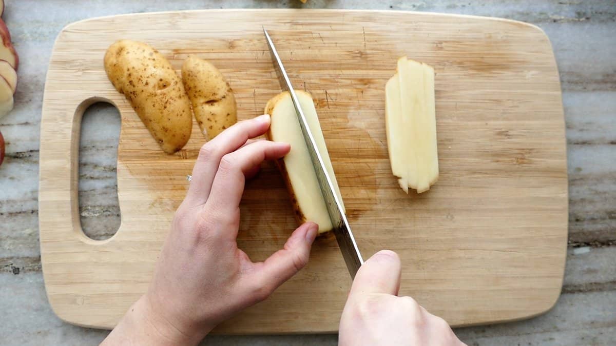 woman cutting a russet potato into sticks
