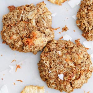 2 morning glory breakfast cookies next to each other surrounded by ingredients and more cookies