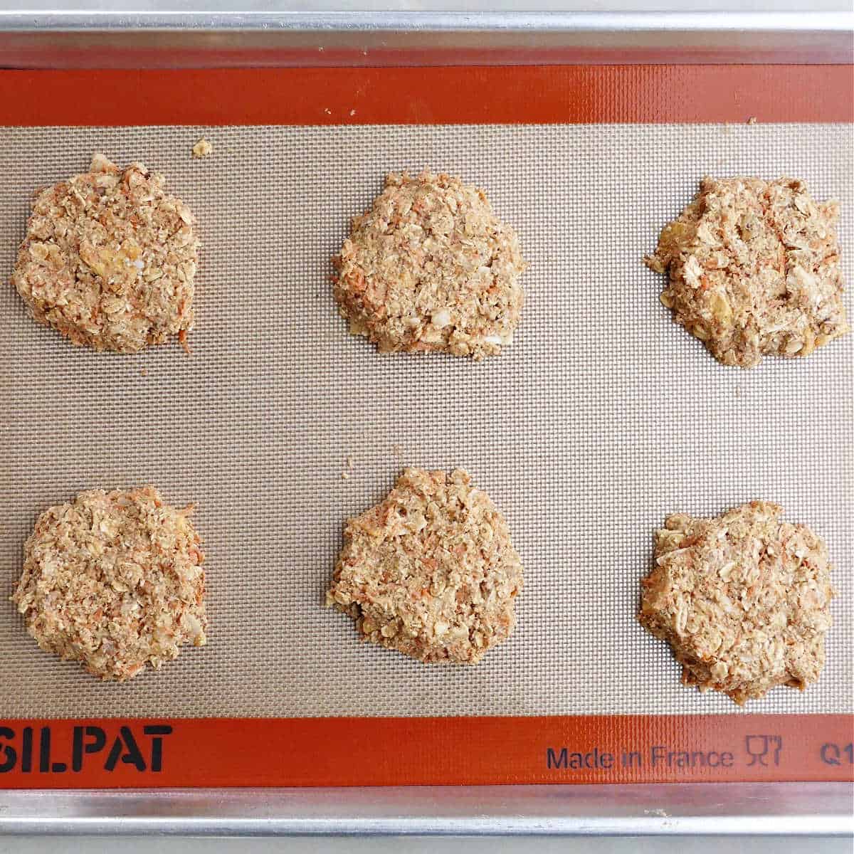 6 morning glory breakfast cookies on a lined baking sheet before going into the oven