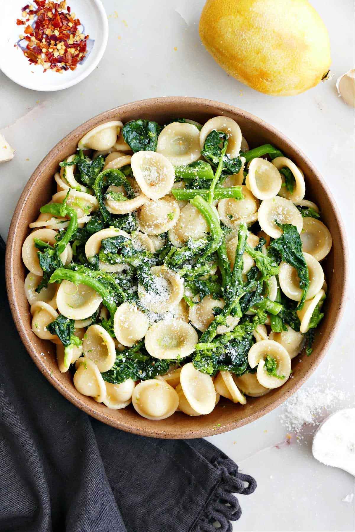 rapini pasta in a bowl next to a napkin and other ingredients