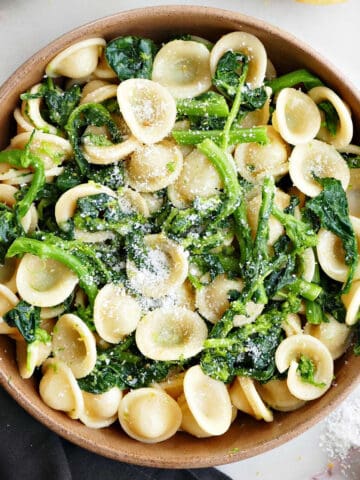 rapini pasta in a bowl next to a napkin and other ingredients