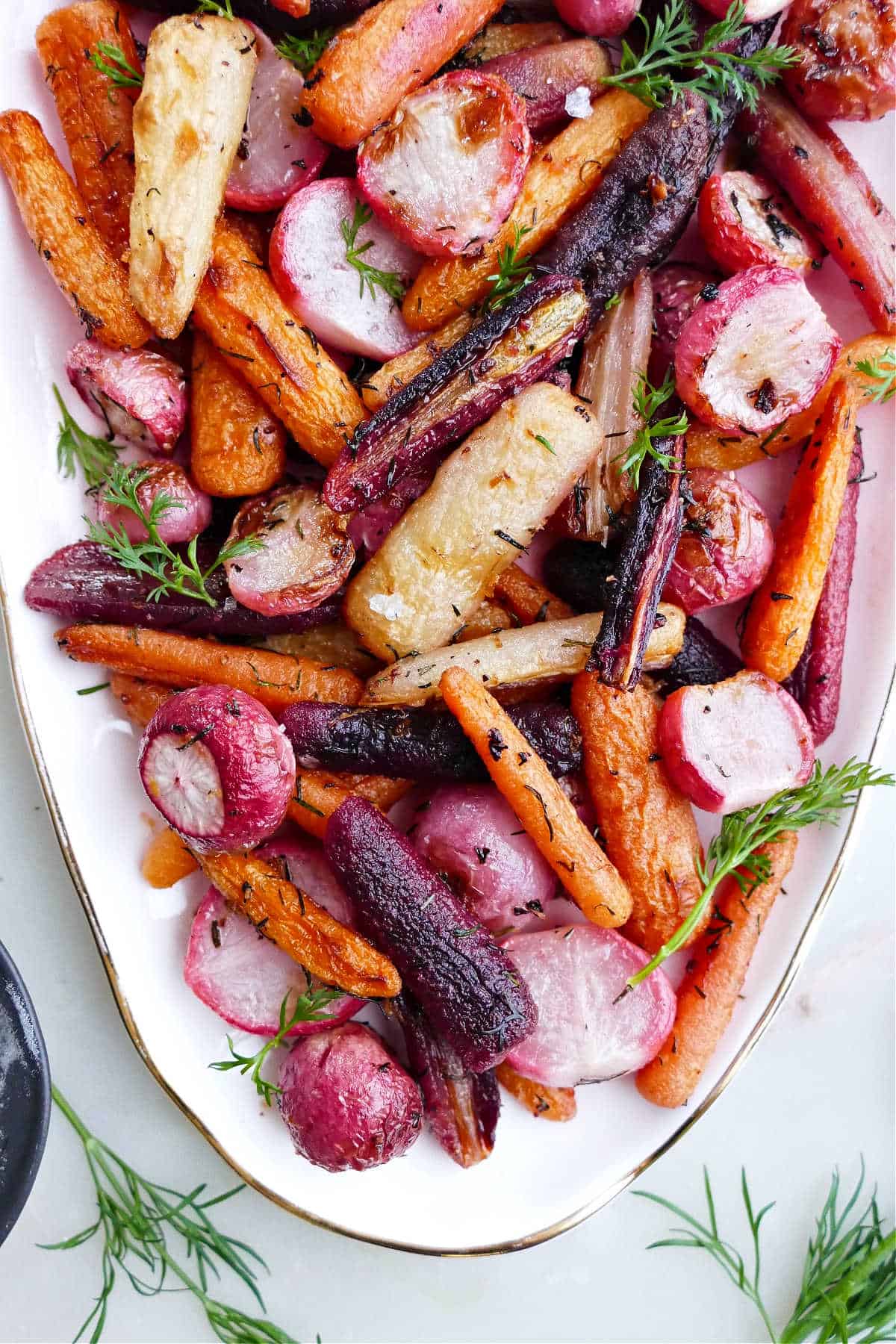 baked radishes and carrots with herbs and butter on a serving tray