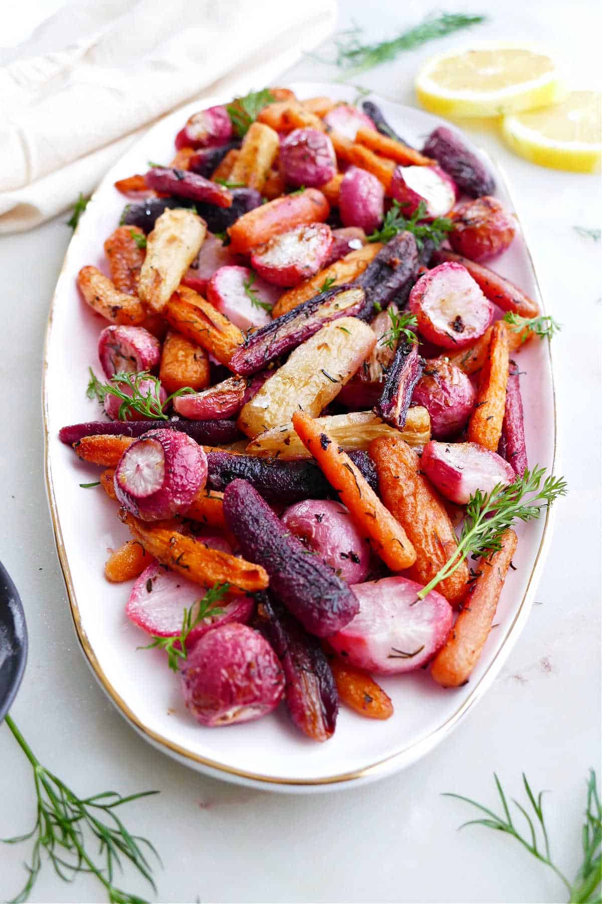 Radishes and carrots sprinkled with dill on a serving tray. 