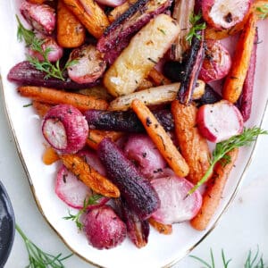 baked radishes and carrots with herbs and butter on a serving tray