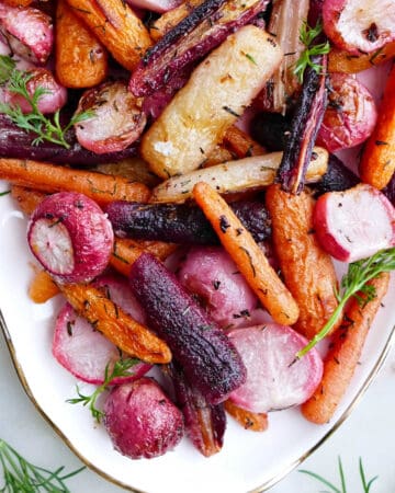 baked radishes and carrots with herbs and butter on a serving tray