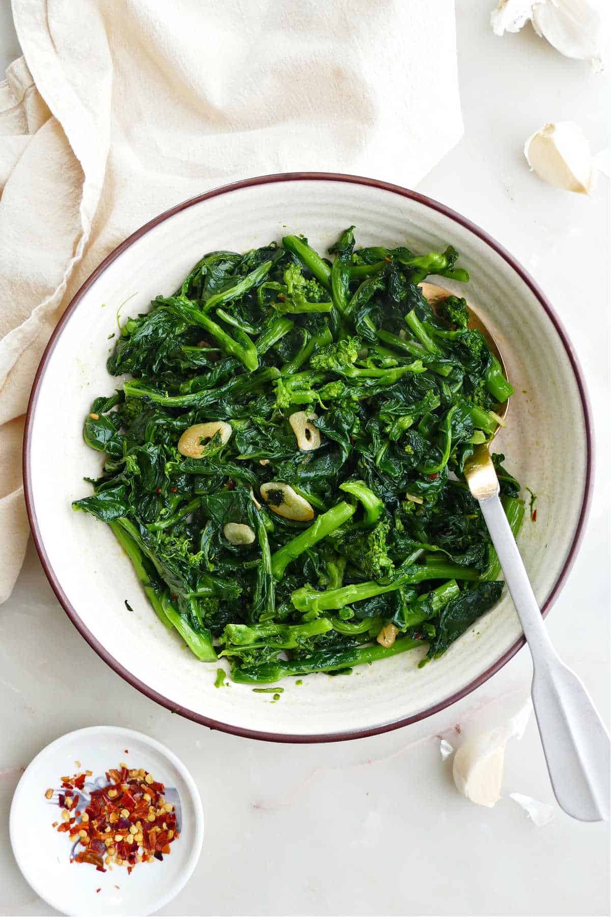 sauteed rapini with garlic in a serving dish with a spoon