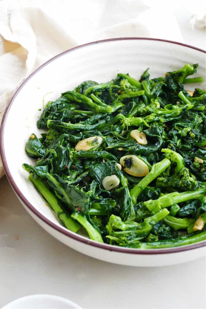 broccoli rabe, garlic, and olive oil in a serving bowl on a counter