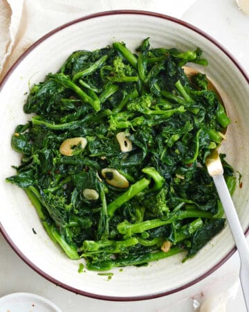 sauteed rapini with garlic in a serving dish with a spoon