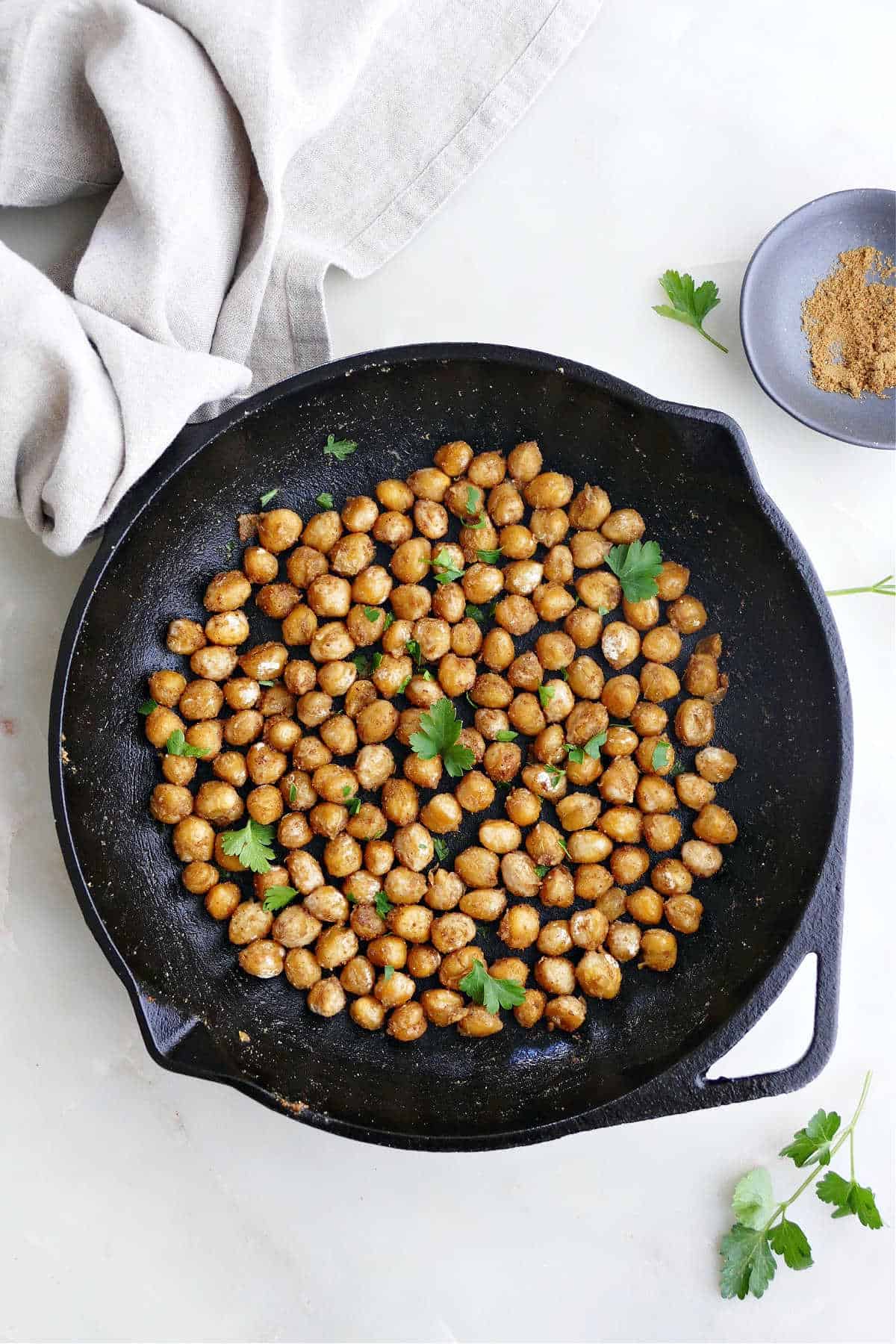 sautéed chickpeas topped with parsley in a cast iron skillet on a counter