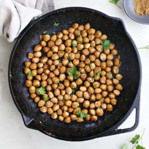 sautéed chickpeas topped with parsley in a cast iron skillet on a counter