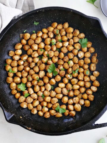 sautéed chickpeas topped with parsley in a cast iron skillet on a counter