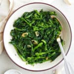 sauteed rapini with garlic in a serving dish with a spoon
