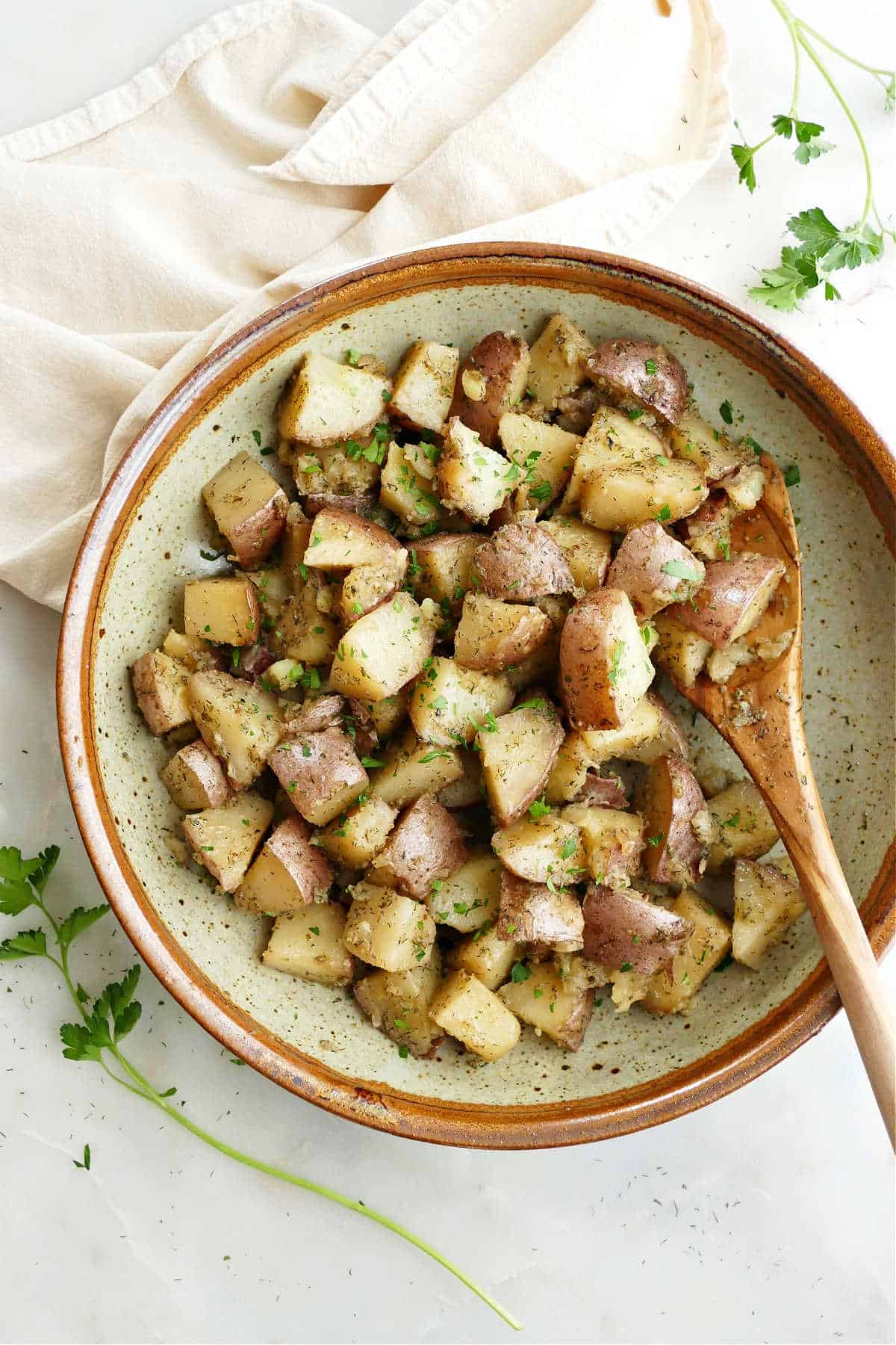 slow cooker potatoes in a serving bowl topped with chopped parsley