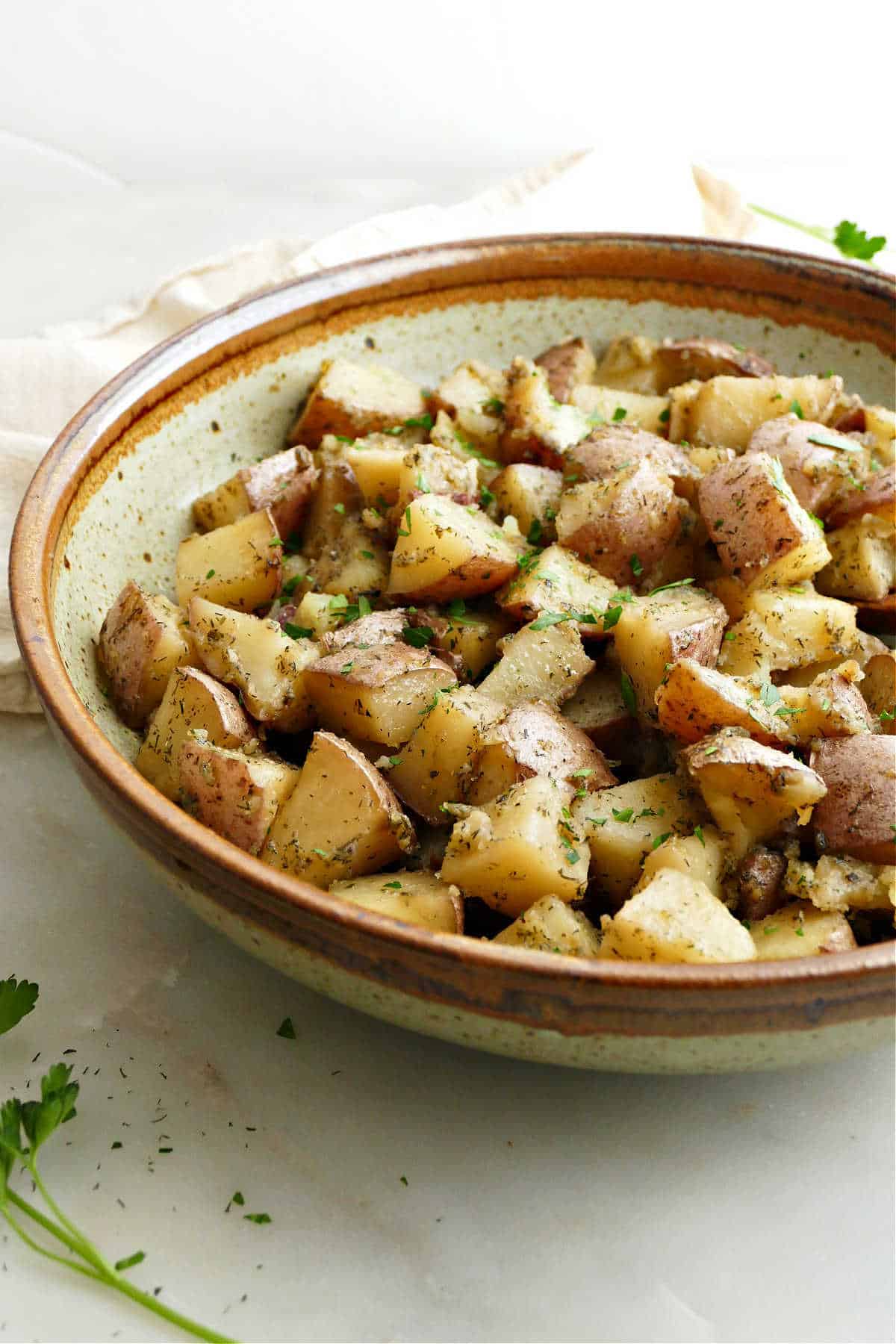 slow cooker potatoes in a serving bowl topped with chopped parsley