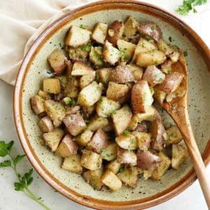 slow cooker potatoes in a serving bowl topped with chopped parsley