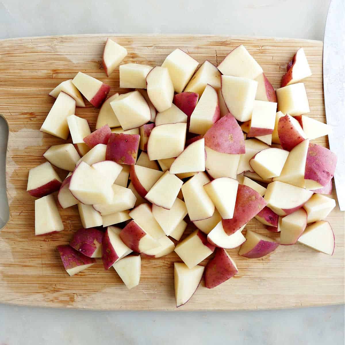 red potatoes cut into chunks on a bamboo cutting board