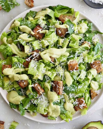 avocado Caesar salad on a large serving plate surrounded by ingredients