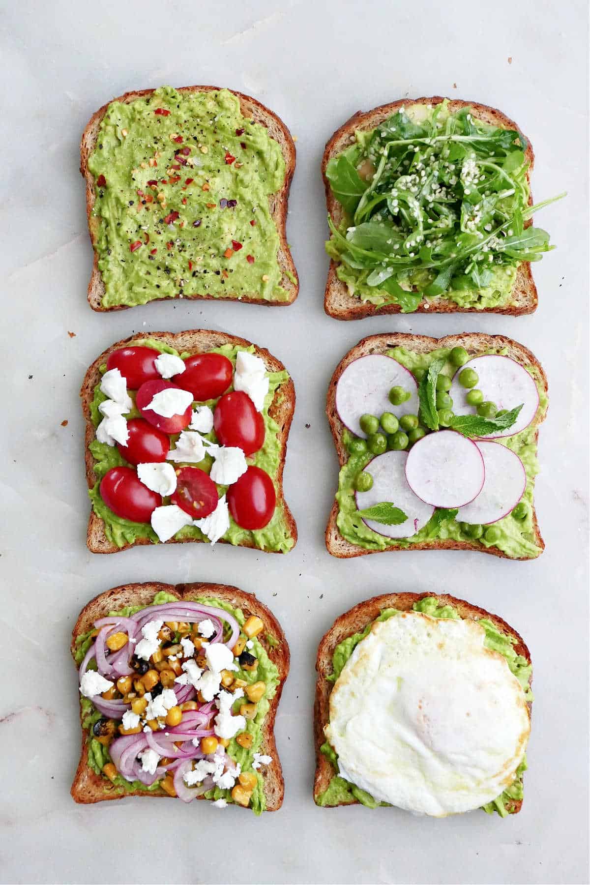 avocado toasts with different toppings next to each other on a counter