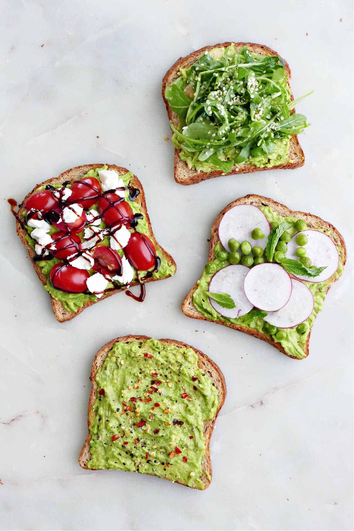 avocado toast with arugula, caprese, radishes and peas, and classic seasonings on a counter