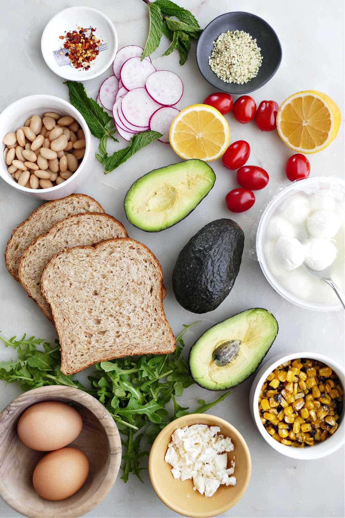 bread, avocados, and toppings for avocado toast spread out on a counter