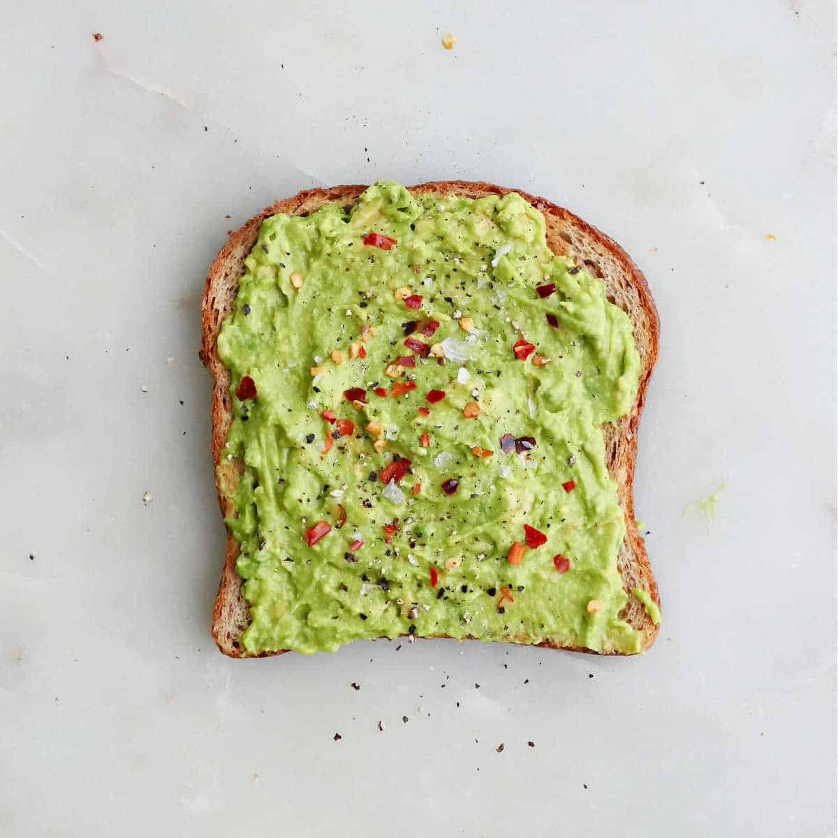 classic avocado toast topped with salt, pepper, and red pepper flakes