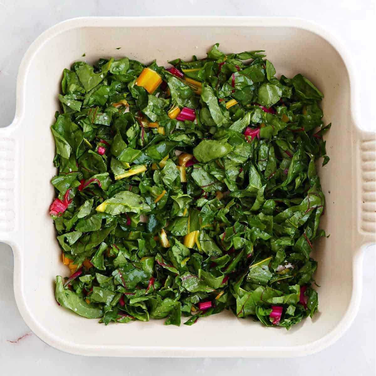 chard leaves and stems spread out in a square casserole dish
