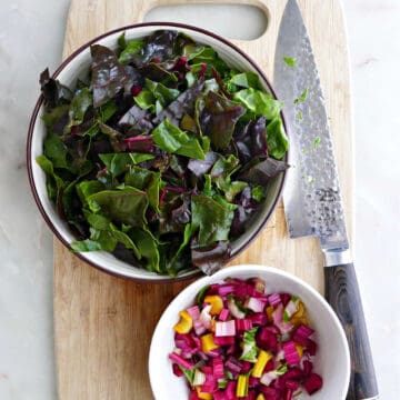 cut Swiss chard leaves and stems in bowls on a cutting board with a knife