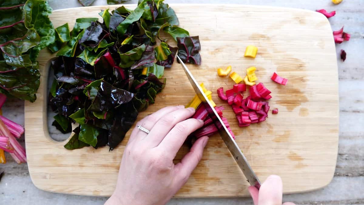 woman slicing rainbow Swiss chard stems on a cutting board