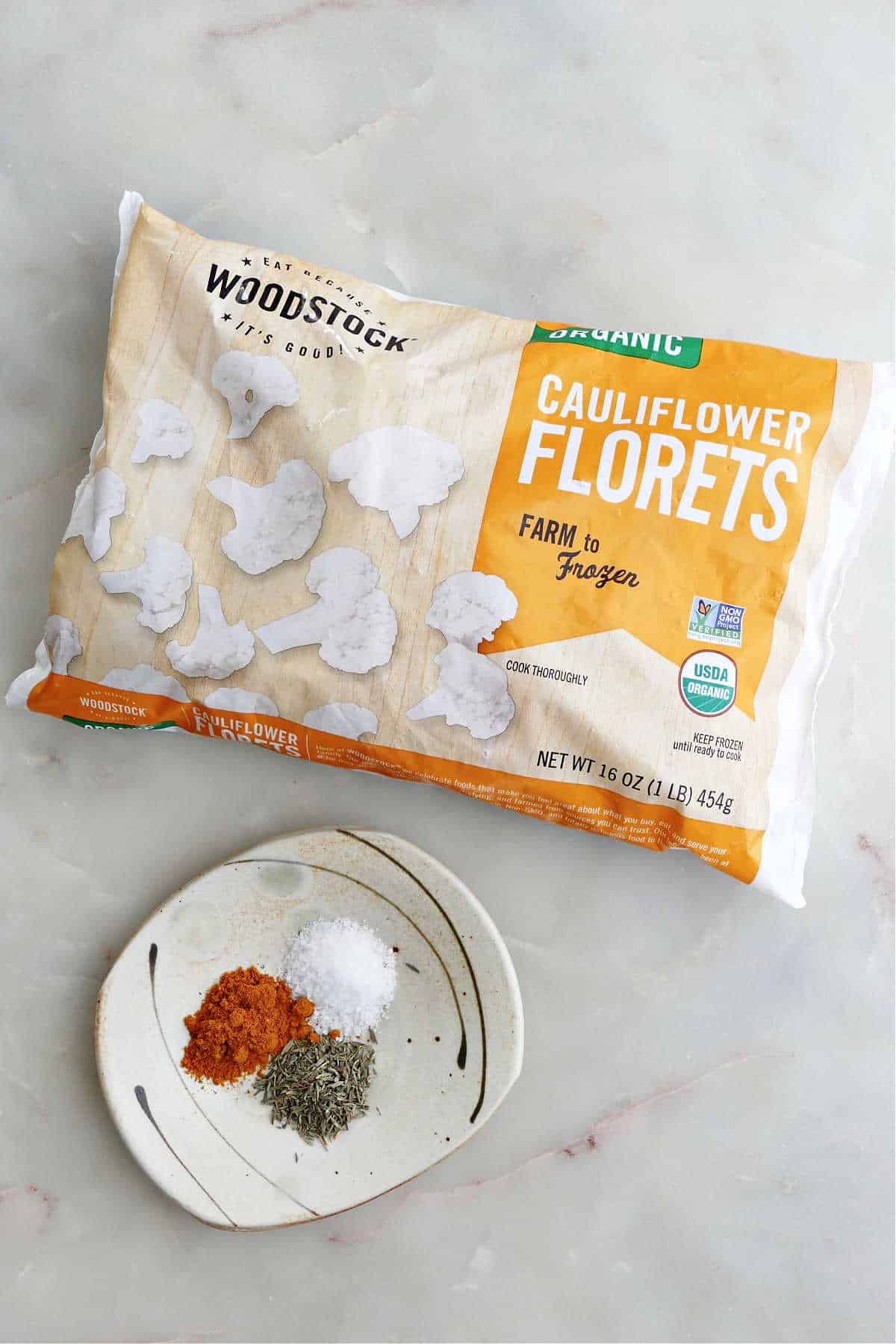 bag of frozen cauliflower next to seasonings on a counter