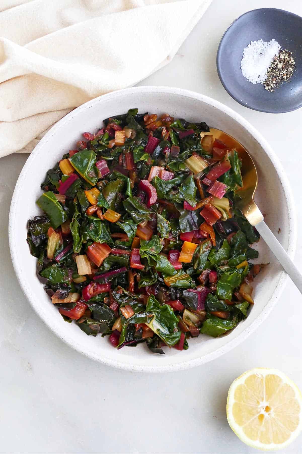 steamed Swiss chard in a serving bowl on a counter next to ingredients