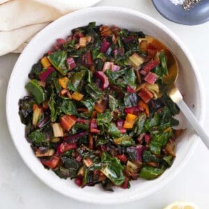 steamed Swiss chard in a serving bowl on a counter next to ingredients