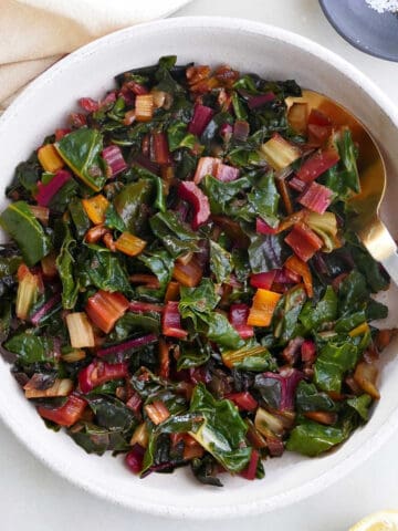 steamed Swiss chard in a serving bowl on a counter next to ingredients