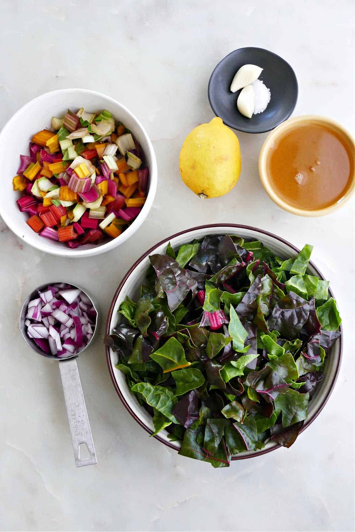 rainbow chard stems, leaves, red onion, broth, lemon, garlic, and salt on a counter