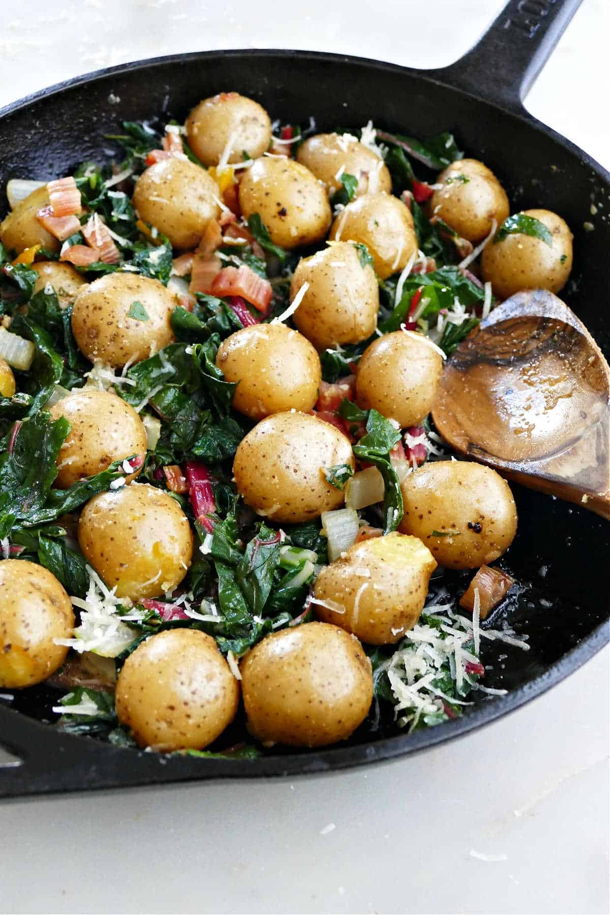 potatoes and Swiss chard leaves and stems in a cast iron skillet