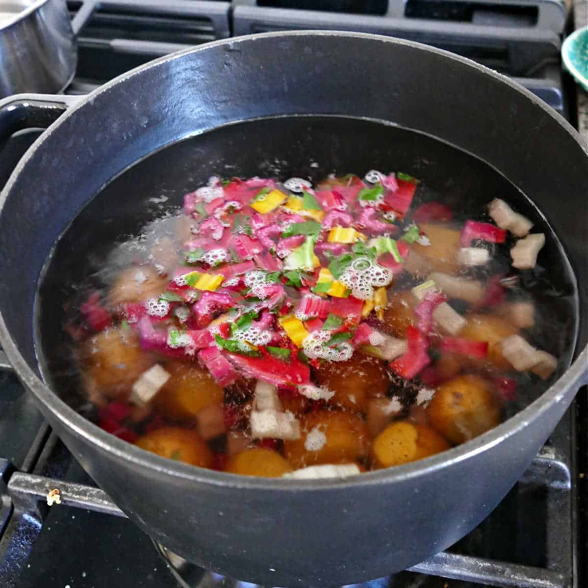 potatoes and chard stems cooking in a pot of boiling water on the stove