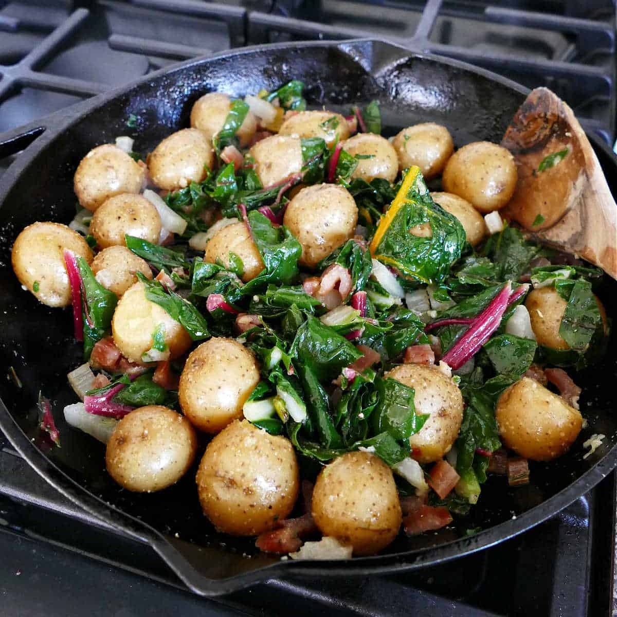 Swiss chard and potatoes cooking in olive oil and garlic in a skillet