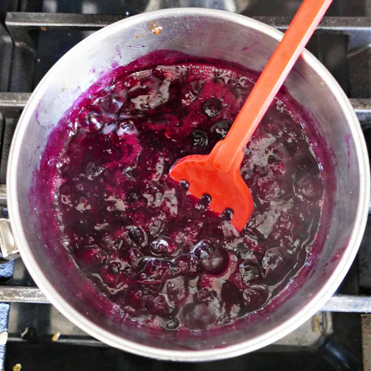 blueberries cooking in a saucepan on a stove to make jam