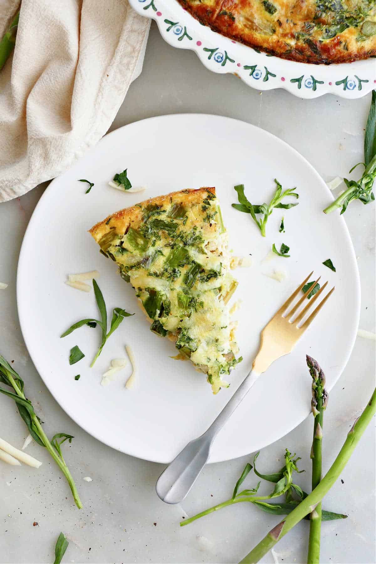 a slice of asparagus quiche on a plate with a fork on a counter