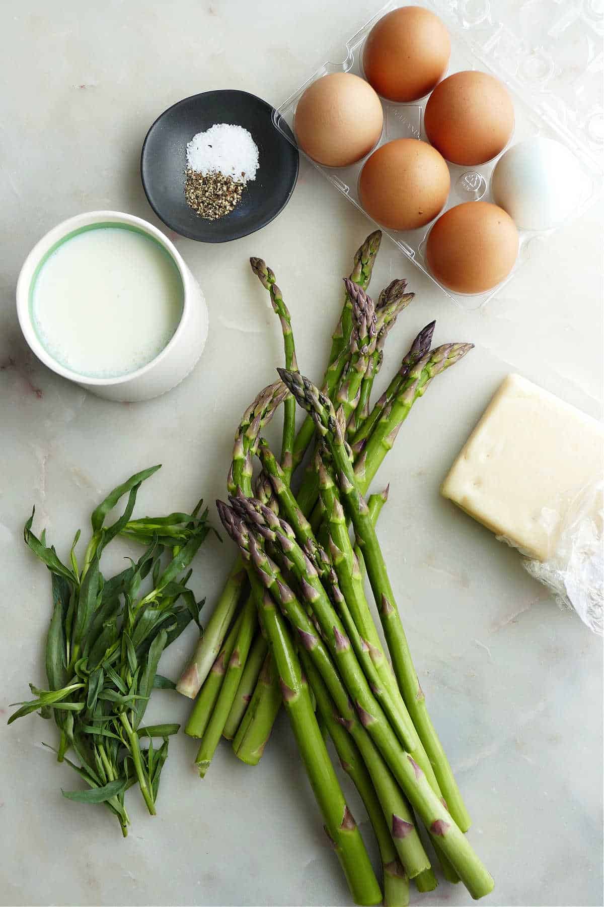 milk, seasonings, eggs, asparagus, Swiss cheese, and tarragon on a counter