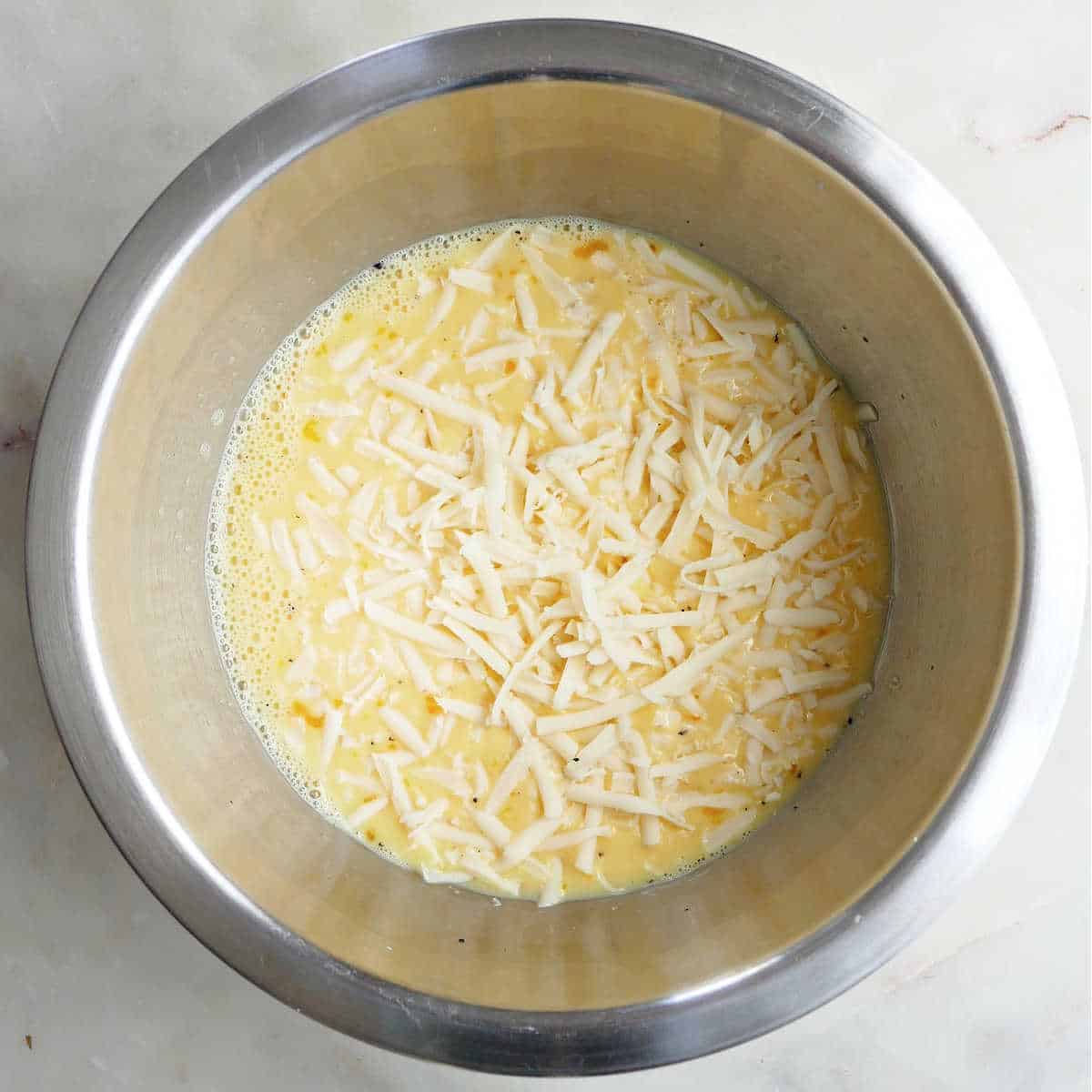 eggs whisked together with milk, cheese, and seasonings in a bowl