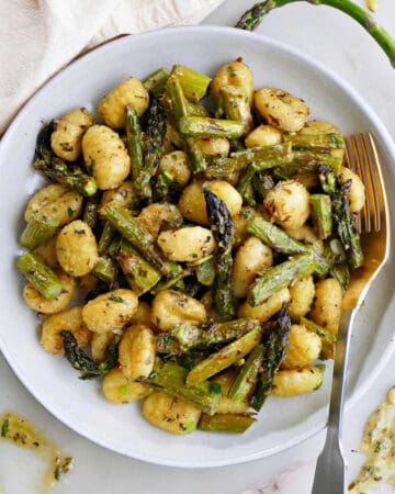 gnocchi with asparagus and lemon dressing on a serving plate with a fork