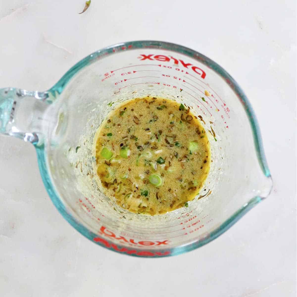 ingredients for Meyer lemon tarragon dressing in a measuring cup on a counter