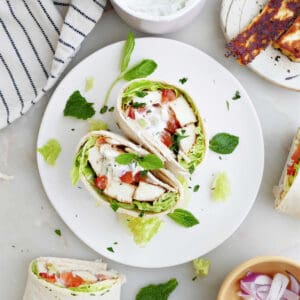 halloumi wrap sliced in half on a serving plate surrounded by ingredients