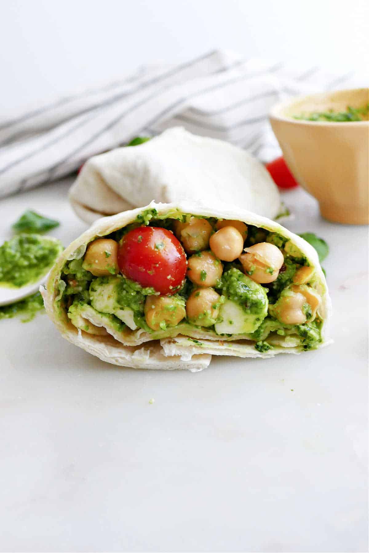 half of a vegetarian pesto wrap with chickpeas on a counter